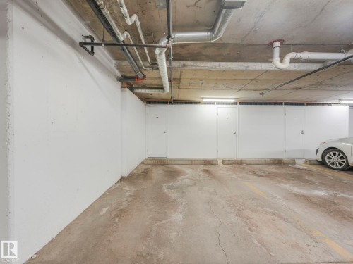 Underground parking space featuring a concrete floor, overhead piping, and fluorescent lighting - 317 2420 108 Street, Edmonton, AB - Indoor Photo Showing Garage