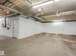 Concrete flooring with visible utility piping and fluorescent lighting - 