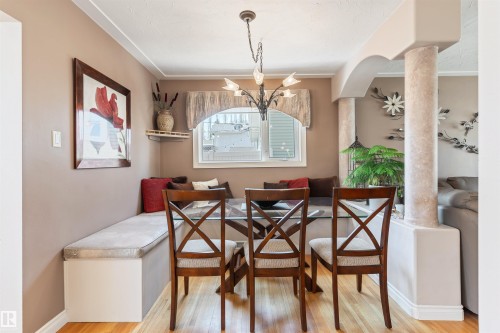 Dining area featuring wood-finish flooring, a built-in bench seating area, and a ceiling-mounted chandelier - 10803 52 Street, Edmonton, AB - Indoor
