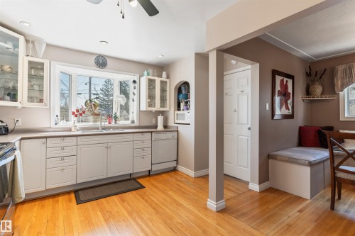 Kitchen featuring wood-finish flooring, light cabinetry, and a bay window - 10803 52 Street, Edmonton, AB - Indoor Photo Showing Kitchen