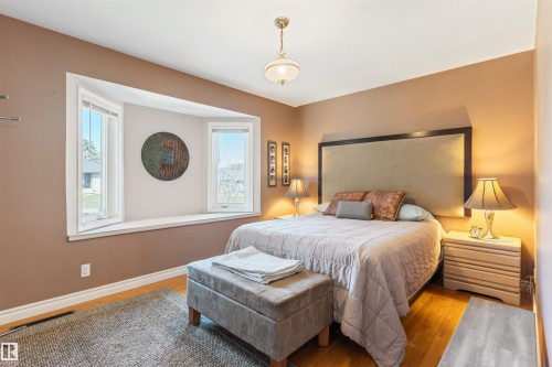 Bedroom featuring hardwood flooring, a bay window with a deep sill, neutral-toned walls, and a ceiling-mounted light fixture - 10803 52 Street, Edmonton, AB - Indoor Photo Showing Bedroom