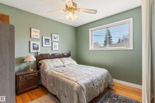 Bedroom featuring hardwood flooring, a ceiling fan with integrated lighting, and a double-hung window - 10803 52 Street, Edmonton, AB - Indoor Photo Showing Bedroom