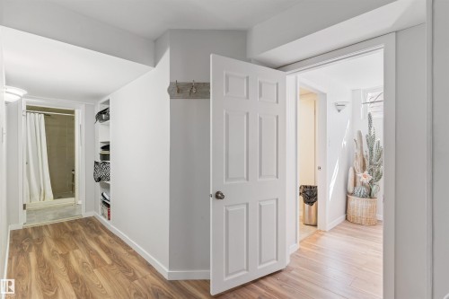 Wood-finish flooring throughout, featuring a doorway to a bathroom with a shower and a built-in shelving unit - 10803 52 Street, Edmonton, AB - Indoor Photo Showing Other Room