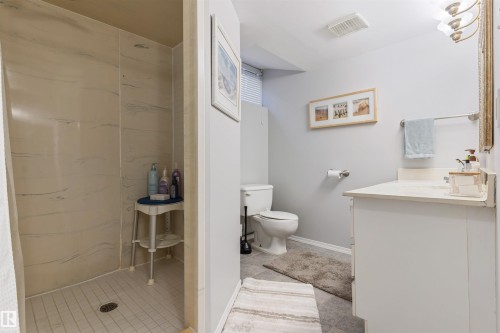 Three-piece bathroom featuring a walk-in shower with tile flooring, a white vanity with a single basin, and a toilet - 10803 52 Street, Edmonton, AB - Indoor Photo Showing Bathroom