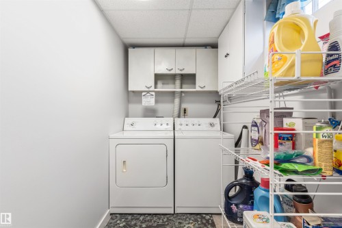 Dedicated laundry area featuring white washer and dryer units, overhead cabinetry, and a drop ceiling - 10803 52 Street, Edmonton, AB - Indoor Photo Showing Laundry Room