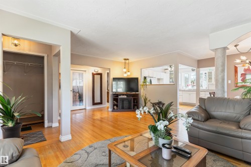 Open-concept living area featuring wood-finish flooring, a partial wall opening to the kitchen, and a built-in entertainment console - 10803 52 Street, Edmonton, AB - Indoor Photo Showing Living Room