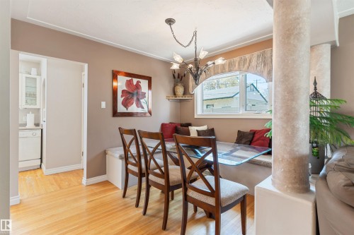 Dining area featuring wood-finish flooring, built-in window seating, and a decorative chandelier - 10803 52 Street, Edmonton, AB - Indoor Photo Showing Dining Room