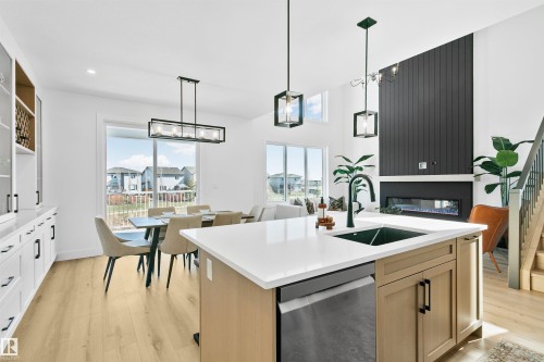 Modern kitchen island featuring a white countertop, integrated sink, and stainless steel dishwasher - 34 Harley Way, Spruce Grove, AB - Indoor Photo Showing Kitchen With Upgraded Kitchen