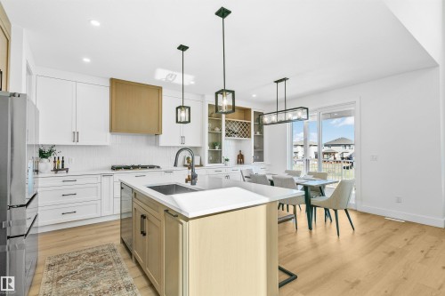 Modern kitchen featuring a central island with an undermount sink, white countertops, and a full suite of stainless steel appliances - 34 Harley Way, Spruce Grove, AB - Indoor Photo Showing Kitchen With Upgraded Kitchen