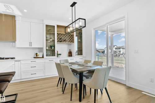 Open-concept dining area featuring light wood-finish flooring and a contemporary linear chandelier - 34 Harley Way, Spruce Grove, AB - Indoor Photo Showing Dining Room