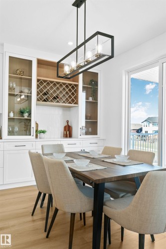 Dedicated dining space featuring wood-finish flooring and a linear chandelier - 34 Harley Way, Spruce Grove, AB - Indoor Photo Showing Dining Room