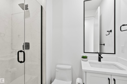 Bathroom featuring a glass-enclosed shower with rain head, white marble-look tile, and matte black fixtures - 34 Harley Way, Spruce Grove, AB - Indoor Photo Showing Bathroom