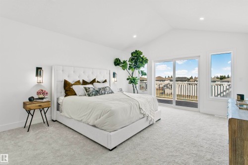 Spacious bedroom featuring vaulted ceilings, soft gray carpeting, a large sliding glass door with balcony access, and two tall windows - 34 Harley Way, Spruce Grove, AB - Indoor Photo Showing Bedroom