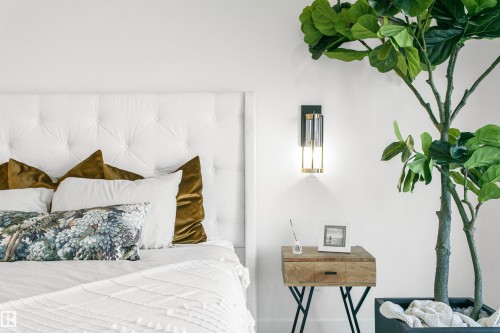 Tufted white headboard with a wall-mounted sconce featuring a clear glass shade and brass-tone accents - 34 Harley Way, Spruce Grove, AB - Indoor Photo Showing Bedroom