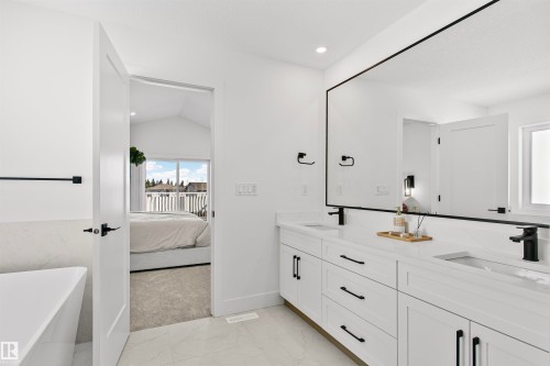 Bathroom vanity featuring dual under-mount sinks, white cabinetry, and matte black fixtures - 34 Harley Way, Spruce Grove, AB - Indoor