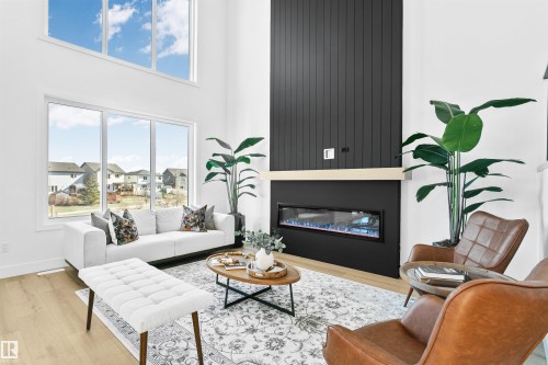Living area featuring high ceilings, a full-height black shiplap accent wall, and a linear electric fireplace with a light wood mantel - 34 Harley Way, Spruce Grove, AB - Indoor Photo Showing Living Room With Fireplace