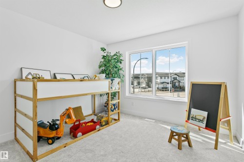 Light-filled interior space with a large window, neutral wall paint, and soft gray carpeting - 34 Harley Way, Spruce Grove, AB - Indoor Photo Showing Other Room
