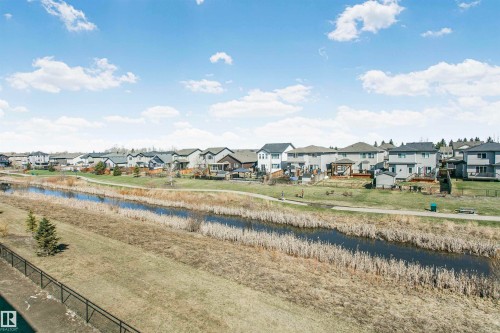 Waterfront property featuring a natural waterway, a walking path, and a row of residential homes with individual backyards - 34 Harley Way, Spruce Grove, AB - Outdoor With View