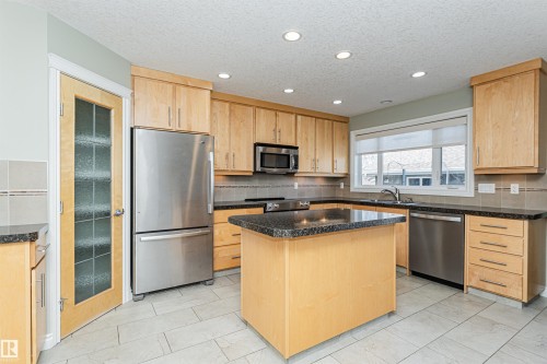 Kitchen featuring light wood cabinetry, granite countertops, stainless steel appliances, and a central island - 8530 76 Avenue, Edmonton, AB - Indoor Photo Showing Kitchen With Double Sink