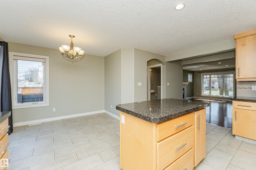Kitchen island featuring a speckled dark countertop and light wood-finish cabinetry with brushed nickel hardware - 8530 76 Avenue, Edmonton, AB - Indoor Photo Showing Kitchen