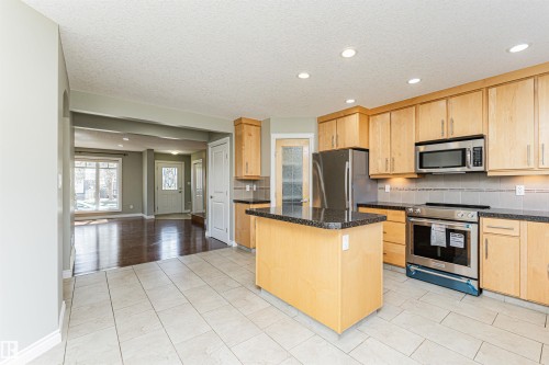Kitchen featuring light wood cabinetry, granite-style countertops, and stainless steel appliances - 8530 76 Avenue, Edmonton, AB - Indoor Photo Showing Kitchen