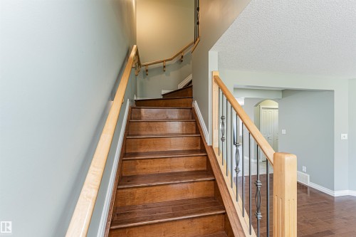 Hardwood staircase with natural wood handrails and wrought iron balusters - 8530 76 Avenue, Edmonton, AB - Indoor Photo Showing Other Room