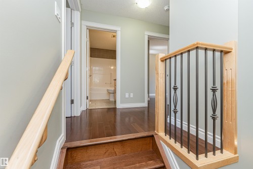 Staircase with wood-finish treads and risers, featuring a decorative wrought iron and natural wood railing - 8530 76 Avenue, Edmonton, AB - Indoor Photo Showing Other Room