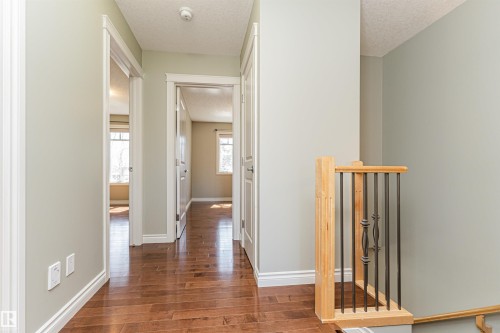 Hallway featuring wood-finish flooring, light neutral wall paint, and white trim - 8530 76 Avenue, Edmonton, AB - Indoor Photo Showing Other Room