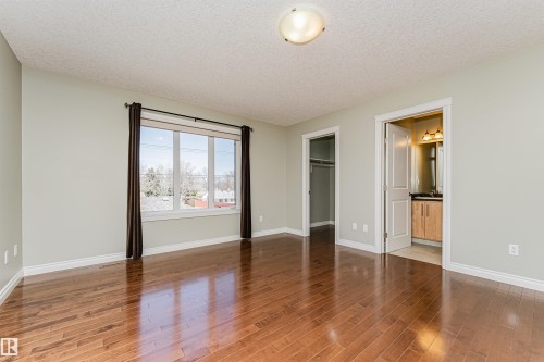 Spacious room featuring wood-finish flooring, a large window, and light-toned walls - 8530 76 Avenue, Edmonton, AB - Indoor Photo Showing Other Room