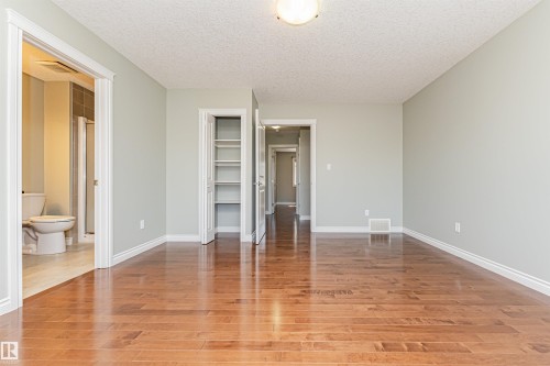 Spacious room featuring wood-finish flooring, light grey walls, and white baseboards - 8530 76 Avenue, Edmonton, AB - Indoor Photo Showing Other Room