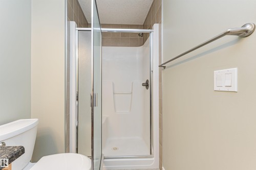 Shower enclosure with clear and frosted glass panels, surrounded by neutral-toned wall tiles - 8530 76 Avenue, Edmonton, AB - Indoor Photo Showing Bathroom