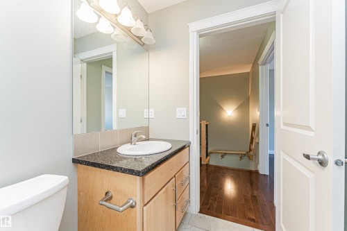 Bathroom vanity featuring a vessel sink, dark stone-finish countertop, and light wood cabinetry - 8530 76 Avenue, Edmonton, AB - Indoor Photo Showing Bathroom