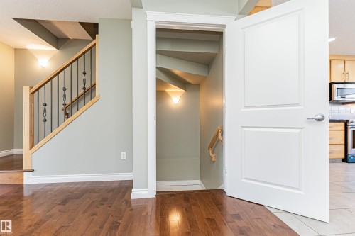 Open paneled door revealing a spiral staircase with a wooden handrail and wall sconce lighting - 8530 76 Avenue, Edmonton, AB - Indoor Photo Showing Other Room