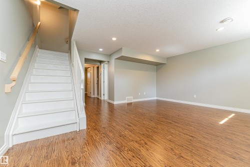 Spacious room featuring wood-finish flooring, light green walls, white trim, and recessed lighting - 8530 76 Avenue, Edmonton, AB - Indoor Photo Showing Other Room