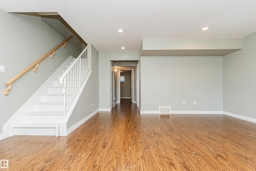 Spacious room featuring wood-finish flooring, light gray wall color, white baseboards, and recessed lighting - 8530 76 Avenue, Edmonton, AB - Indoor Photo Showing Other Room