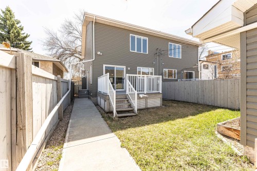Rear exterior featuring gray horizontal siding, a white wood deck with lattice skirting, and a sliding glass door - 8530 76 Avenue, Edmonton, AB - Outdoor With Deck Patio Veranda With Exterior