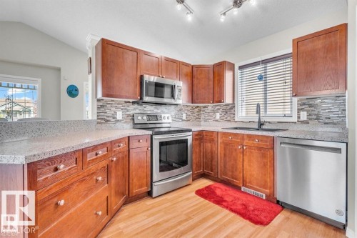 Kitchen featuring warm wood cabinetry, light-toned countertops, and a mosaic tile backsplash - 21223 92 Avenue, Edmonton, AB - Indoor Photo Showing Kitchen