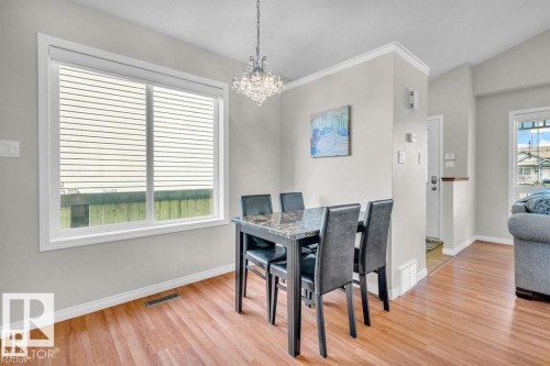 Open-concept dining area featuring wood-finish flooring and a contemporary crystal chandelier - 21223 92 Avenue, Edmonton, AB - Indoor Photo Showing Dining Room