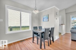 Open-concept dining area featuring wood-finish flooring and a contemporary crystal chandelier - 