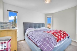 Corner bedroom featuring two vertical windows, light-toned walls, and neutral carpet flooring - 