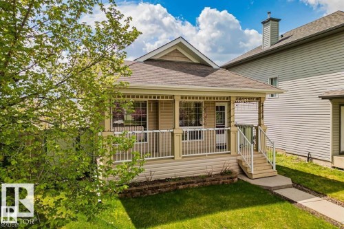 Charming residential exterior featuring a covered front porch with white railing, light-colored siding, and a brown shingle roof - 21223 92 Avenue, Edmonton, AB - Outdoor With Deck Patio Veranda