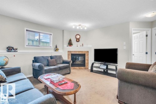 Living area with a corner fireplace featuring a tiled surround and white mantel - 21223 92 Avenue, Edmonton, AB - Indoor Photo Showing Living Room With Fireplace