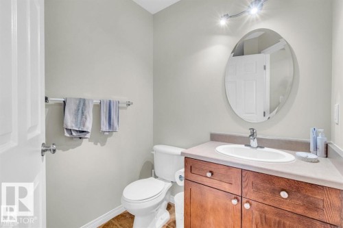 Bathroom with a wood-finish vanity, light-toned countertop, oval mirror, and track lighting - 21223 92 Avenue, Edmonton, AB - Indoor Photo Showing Bathroom
