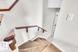 Carpeted staircase with contrasting wood railings and white walls - 