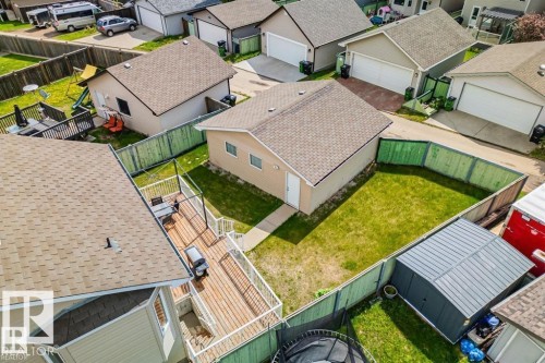 Expansive backyard featuring a detached garage, a large wood deck with white railings, a fenced yard with green fencing, and a separate storage shed - 21223 92 Avenue, Edmonton, AB - Outdoor