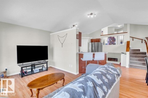Vaulted ceilings enhance this open-concept living area featuring wood-finish flooring - 21223 92 Avenue, Edmonton, AB - Indoor Photo Showing Living Room