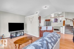 Vaulted ceilings enhance this open-concept living area featuring wood-finish flooring - 