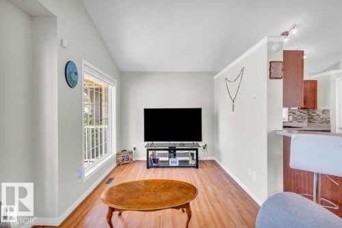 Living area featuring wood-finish flooring, a large window with white trim, and light-colored walls - 21223 92 Avenue, Edmonton, AB - Indoor Photo Showing Living Room
