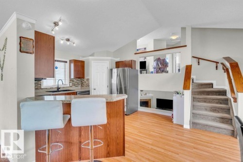 Kitchen with wood-finish cabinetry, granite-look countertops, and a tiled backsplash - 21223 92 Avenue, Edmonton, AB - Indoor