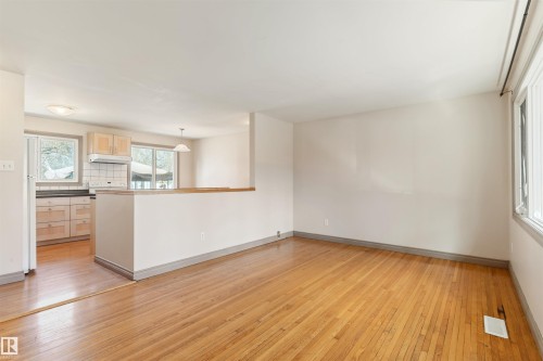 Spacious living area featuring wood-finish flooring and ample natural light from multiple windows - 10620 68 Avenue, Edmonton, AB - Indoor